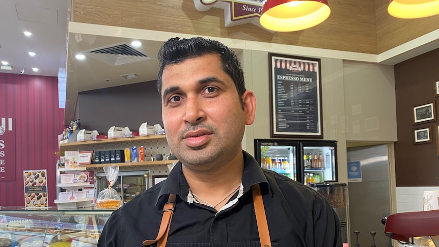 a man in a bakery with a subdued expression