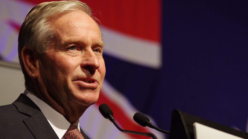 Headshot of WA Premier Colin Barnett with a flag in the background