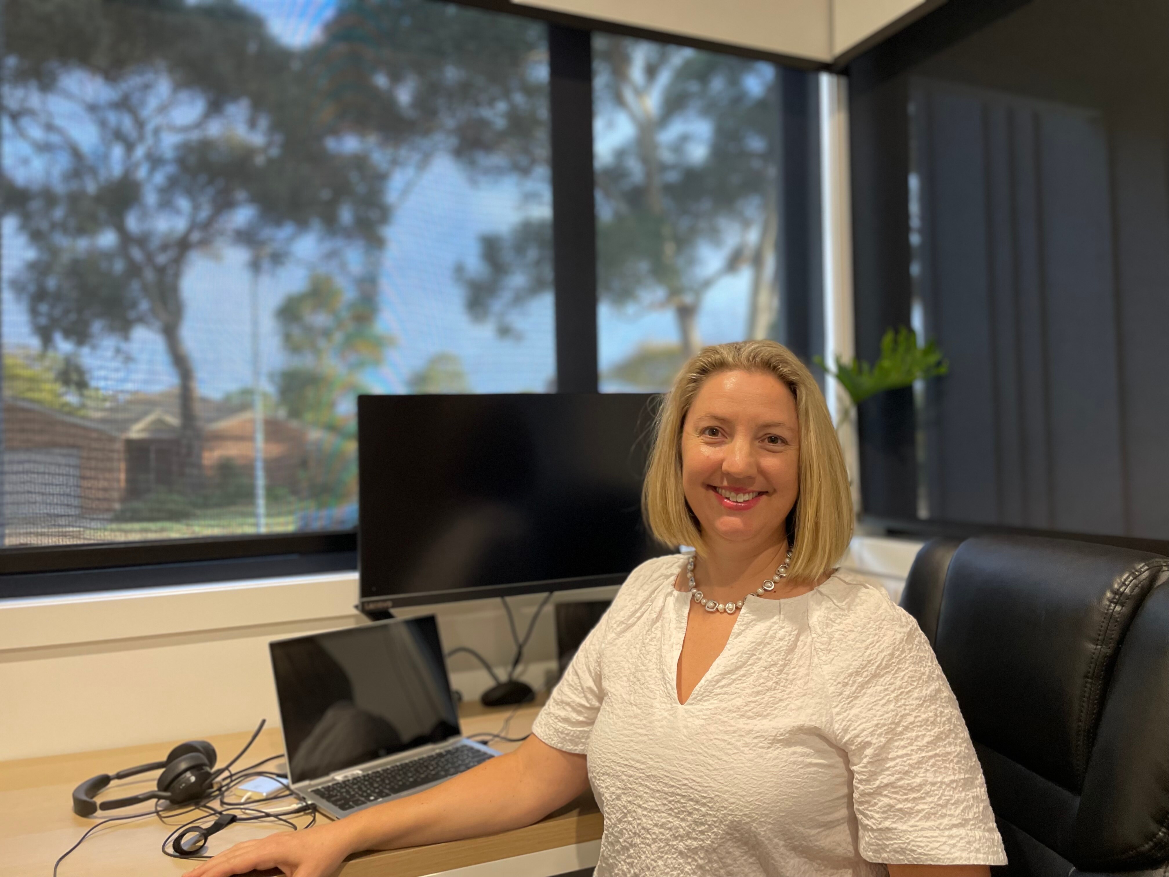 A woman with blonde hair sitting at her home office.