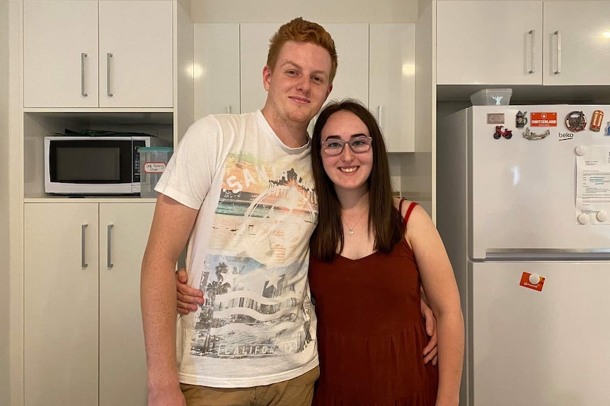 Shaun McGinty and his partner Britney Jeffries hug in the kitchen of their house.