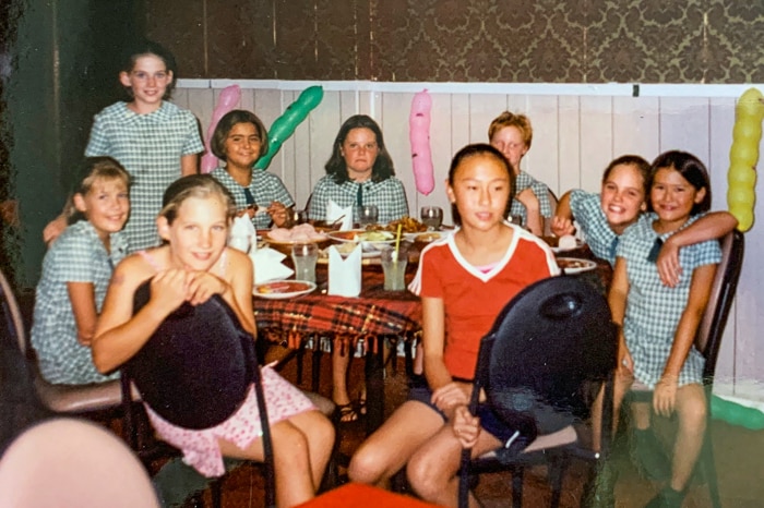 Schoolgirls attending a birthday party  inside a Chinese restaurant dining room.