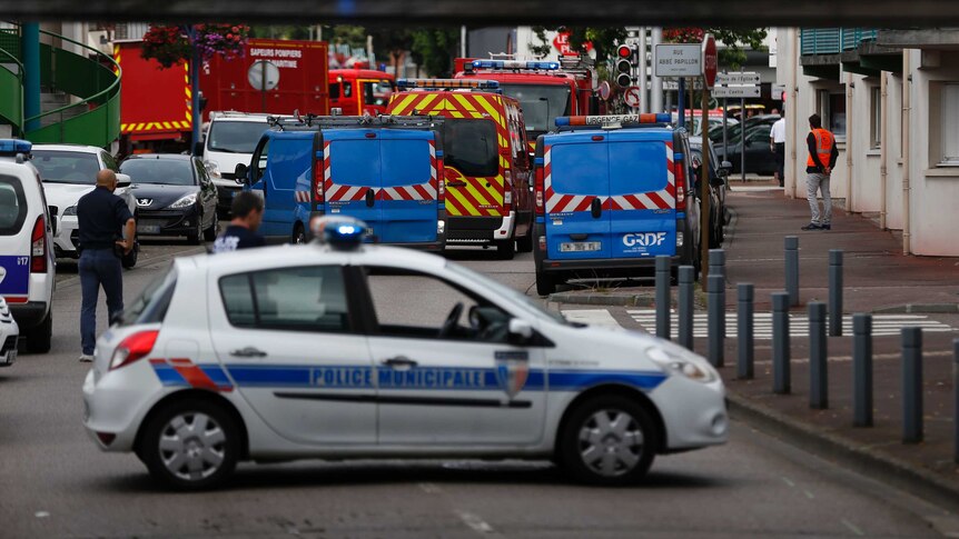 French police vehicles and firemen arrive at the scene of a hostage-taking at a church.