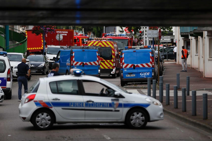 French police vehicles and firemen arrive at the scene of a hostage-taking at a church.