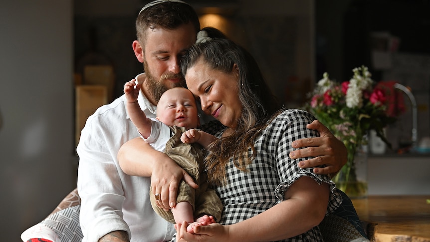 a father and mother holding a tiny baby