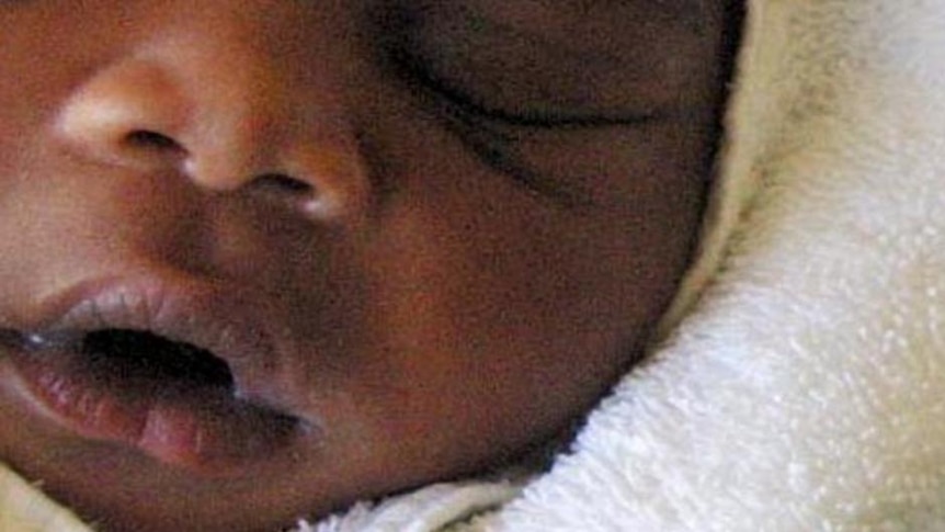 A baby sleeps in her mother's arms next to the anti-AIDS drug Nevirapine