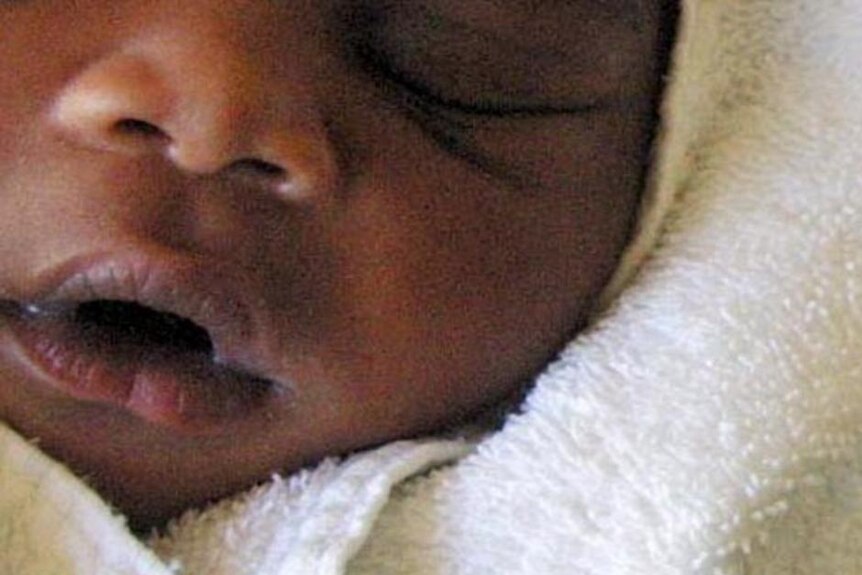 A baby sleeps in her mother's arms next to the anti-AIDS drug Nevirapine