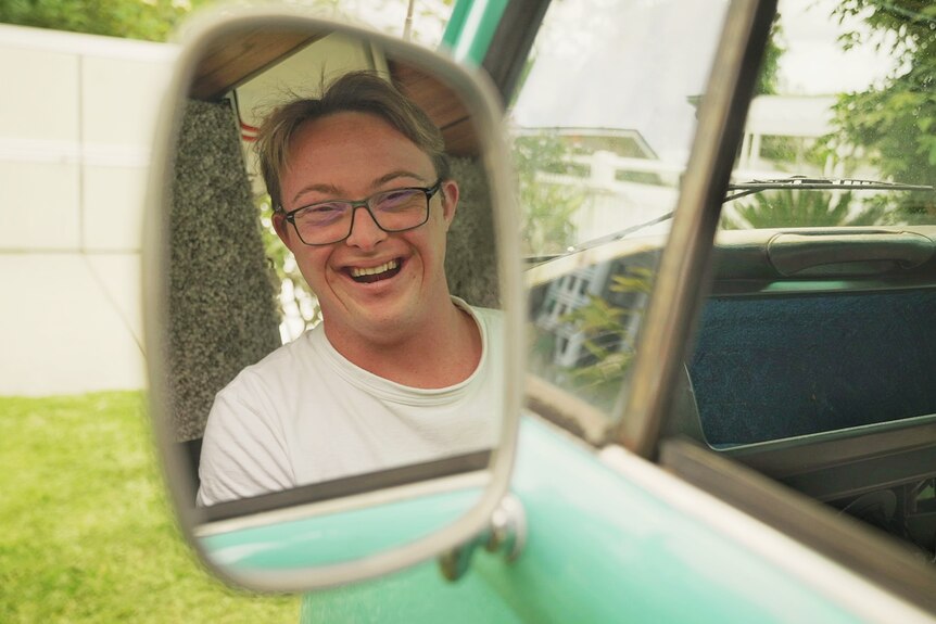 Bobby Pate sonríe en el espejo del coche de su furgoneta kombi barista renovada.