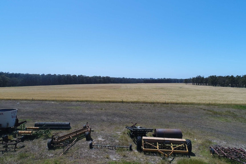 A photo of a paddock with farm machinery and fences.