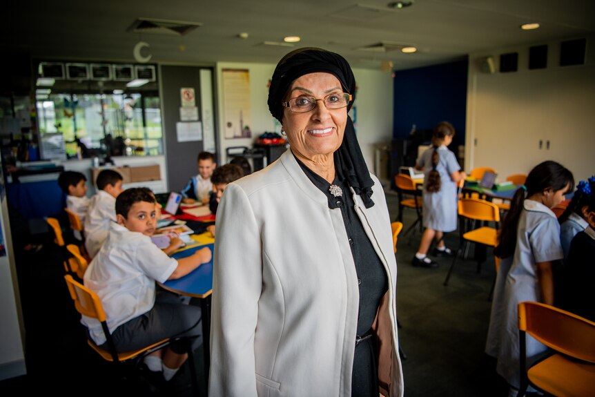 Mona Abdel-Fattah smiling at the camera in a classroom, with small children in the background.