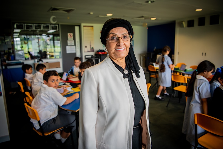 Mona Abdel-Fattah smiling at the camera in a classroom, with small children in the background.