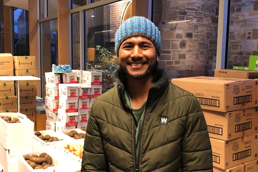 Suvil Karmacharya in front of food boxes.