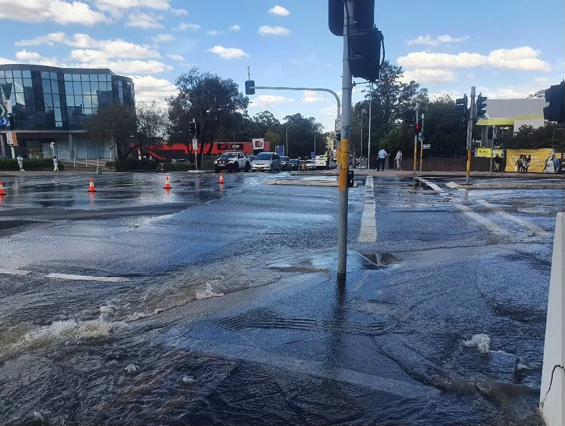 water flowing out of a burst water main into busy streets