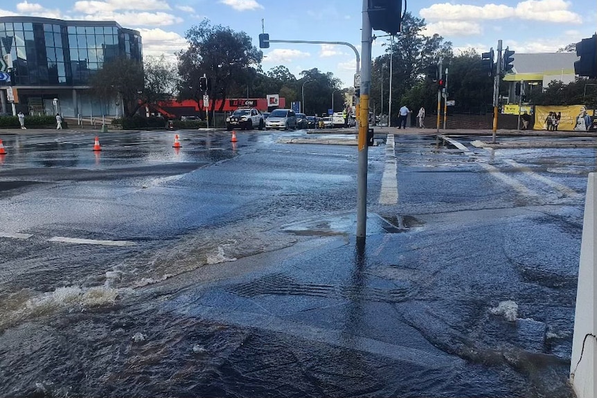 water flowing out of a burst water main into busy streets