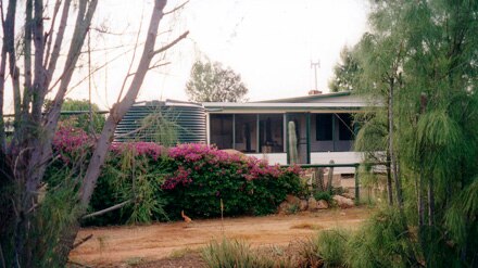 Madura Plains homestead surrounded by trees and shrubs and a water tank