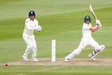 An Australian women's cricketer plays a cut shot as the wicketkeeper watches the ball disappear.