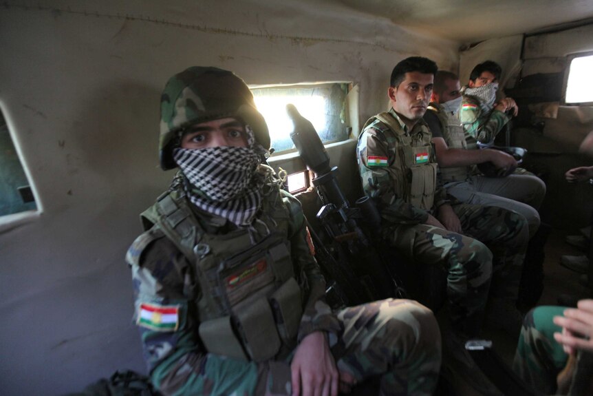 Kurdish Peshmerga forces ride in military vehicles on the south-east of Mosul.