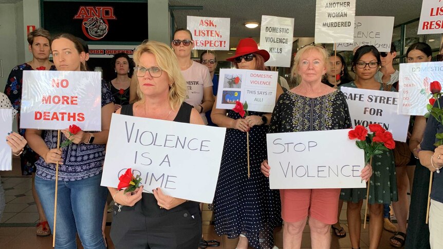 About 20 people with signs at a silent Red Rose rally against domestic violence in Townsville.