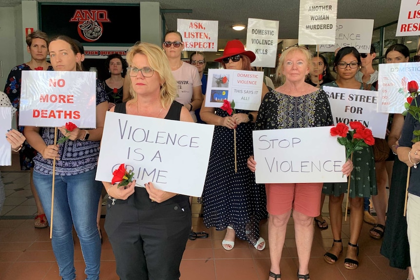 About 20 people with signs at a silent Red Rose rally against domestic violence in Townsville.
