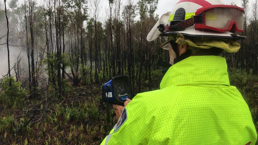 RFS volunteer holds thermal camera up to a hotspot in the Lindfield Park fireground
