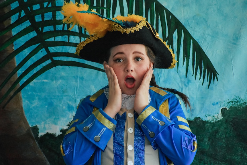 a young performer in a sailor's outfit looks at the camera