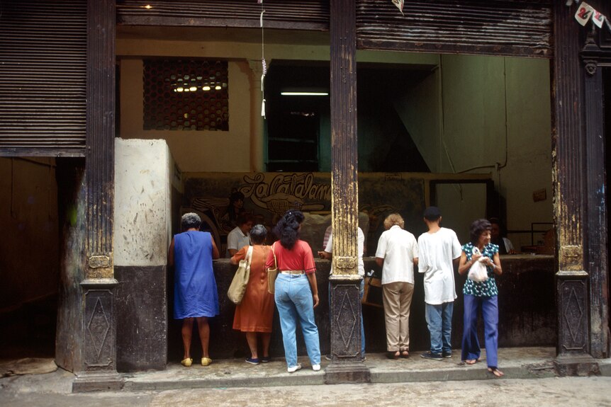 Cuban men and women wait outside a food store in the 1990s.