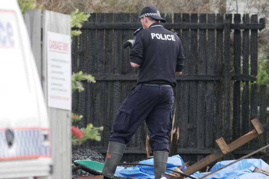 A forensic officer takes photos of rubble.