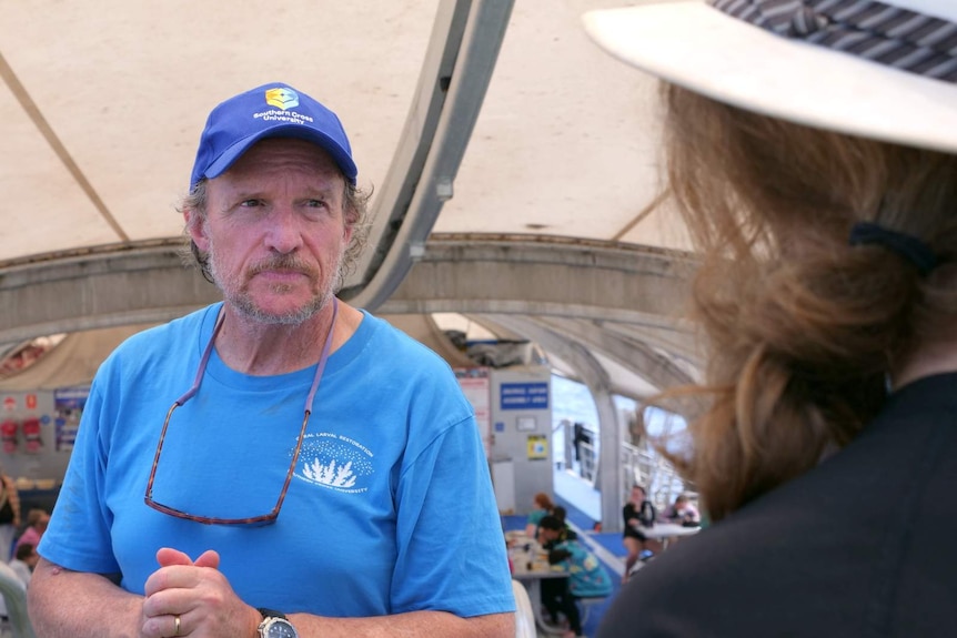 A photo of reef researcher Peter Harrison looking at a tourist on the Great Barrier Reef.