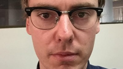 A selfie of a man wearing glasses and looking serious.