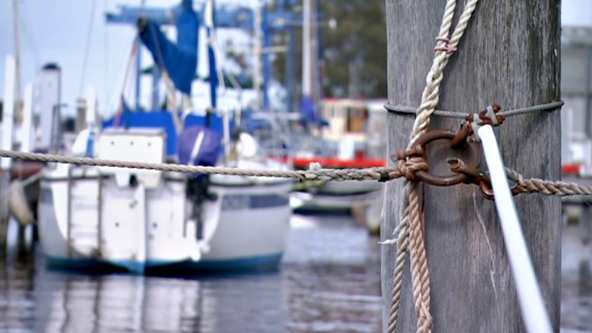 An out-of-focus boat in a harbour with a wooden post on the right.