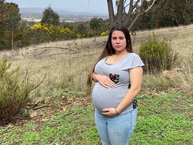 A pregnant woman holds her belly.