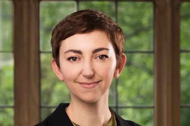 A woman with short hair standing in front of a window.