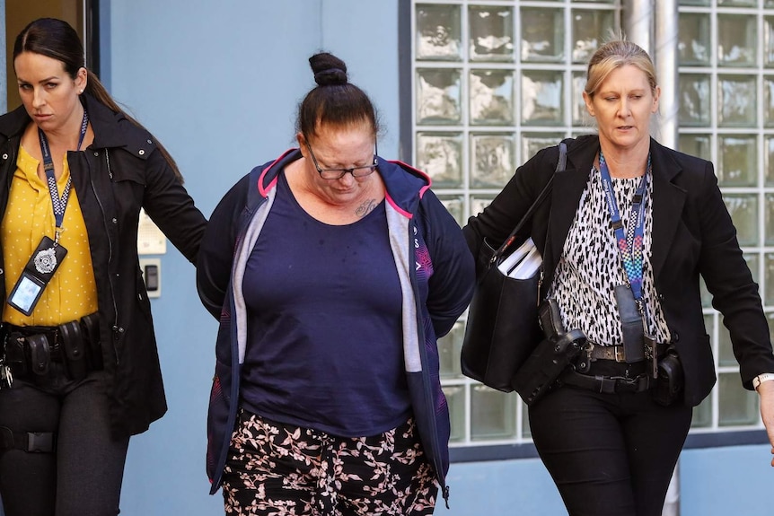 Two female police officers walking with a woman under arrest