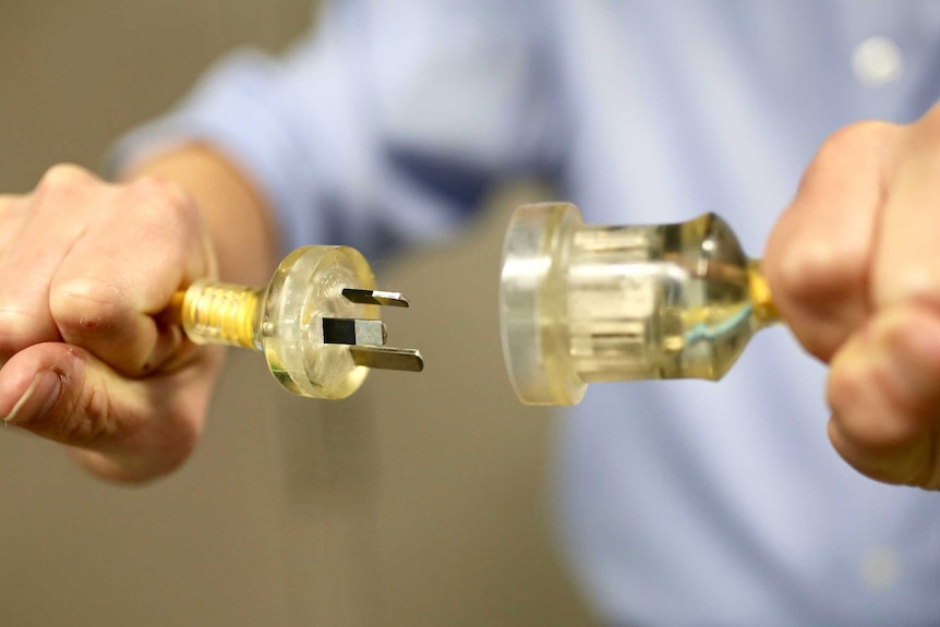 A man holding two ends of a yellow power plug.