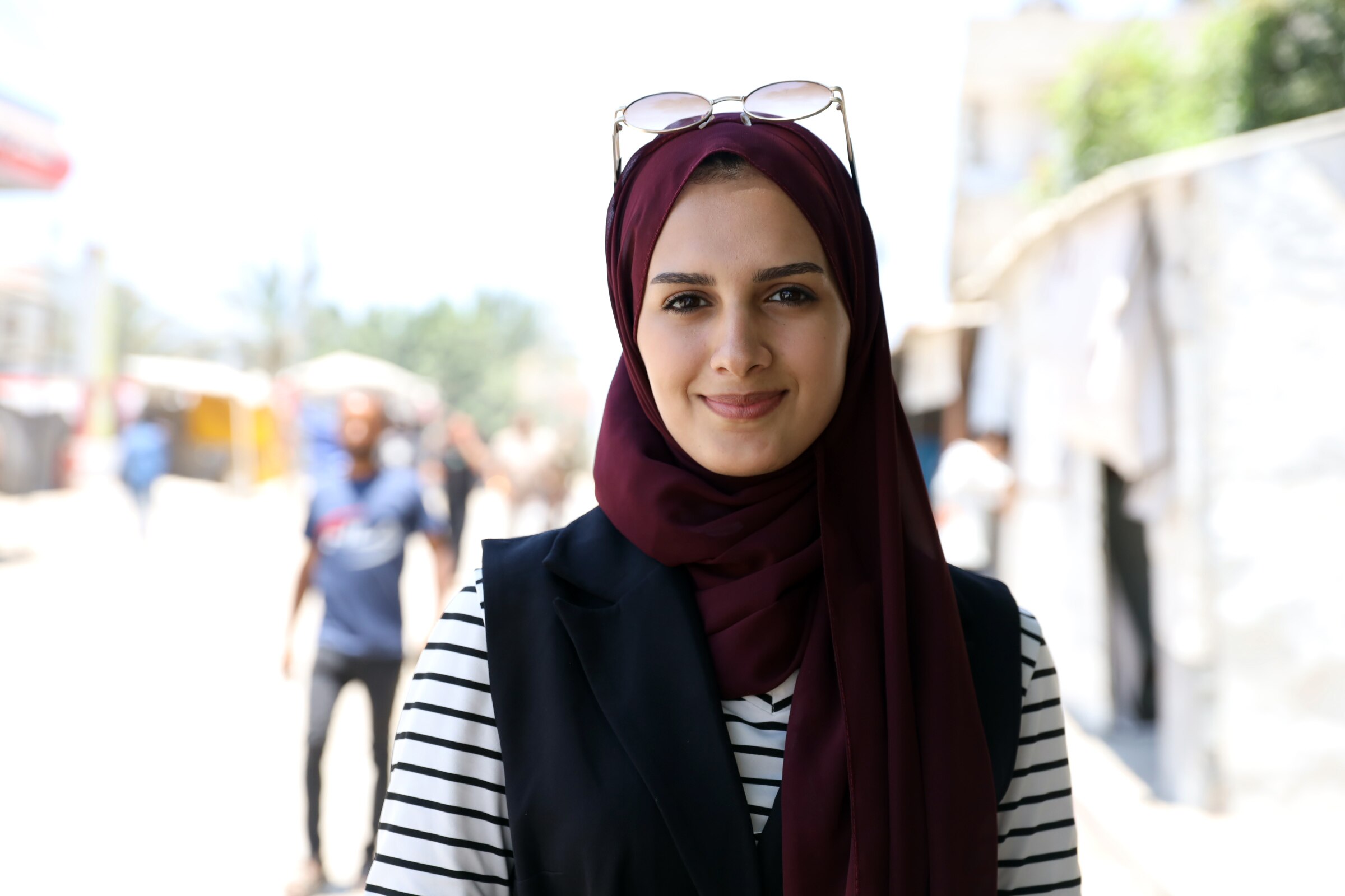 Saja Al-Bahisi smiles as she wears spectacles atop her head and looks into the camera.