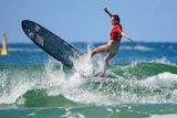The world champion turns her very large surf board at the top of a wave
