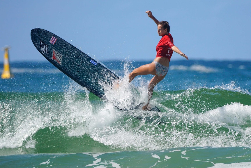 The world champion turns her very large surf board at the top of a wave
