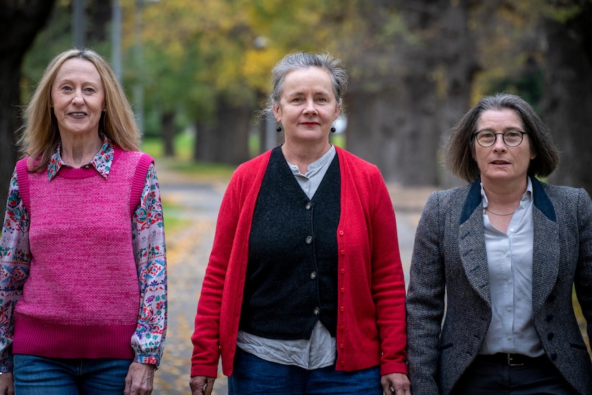 Three palliative care nurses walk down a street.
