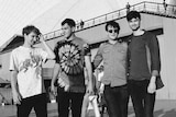 Four members of the band Glass Animals stand for a photo together outside the Sydney Opera House