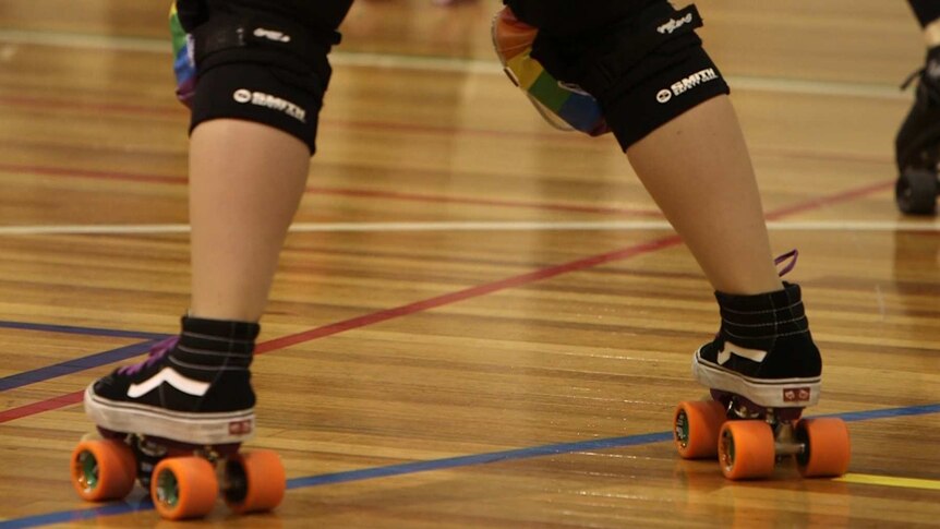 A roller derby competitor wears rainbow kneepads.