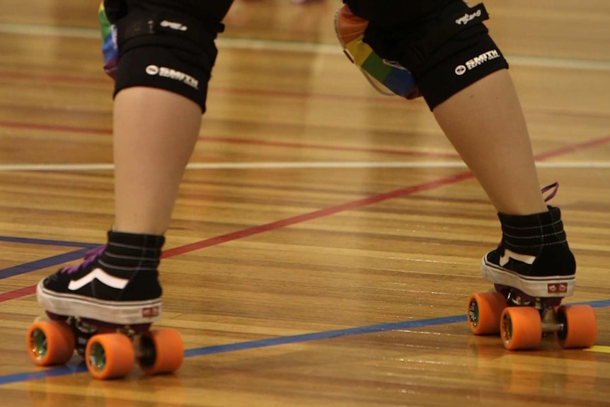 A roller derby competitor wears rainbow kneepads.