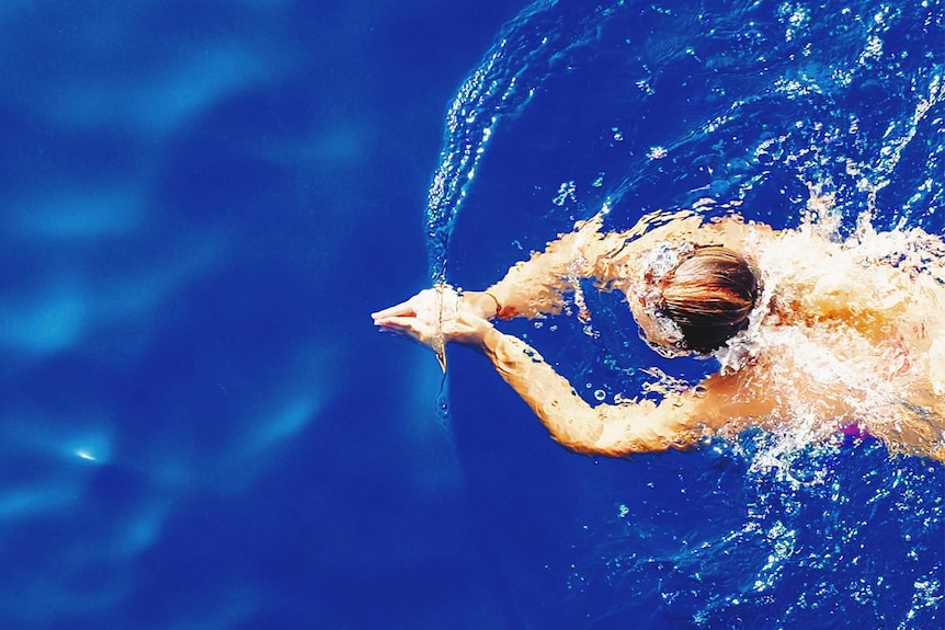 Woman in a bright blue swimming pool for a story about the bare minimum amount of exercise you need to stay healthy.