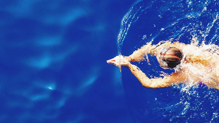 Woman in a bright blue swimming pool for a story about the bare minimum amount of exercise you need to stay healthy.