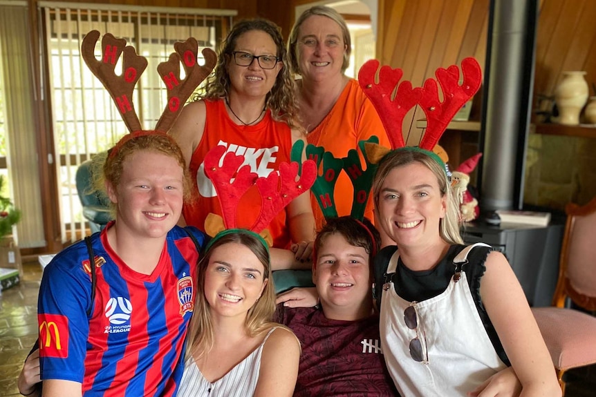 Keely Johnson, second from bottom left, with one sibling on left and two on right and two mums at the back of family photo.