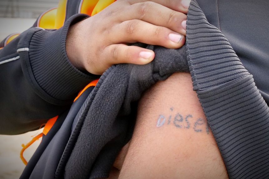 An arm with a stick and poke tattoo saying "diesel"