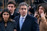 Michael Cohen arrive at federal court holding the arm of his wife. His adult children walk behind.