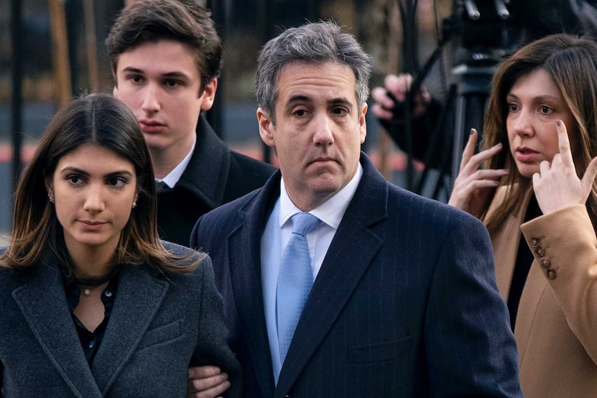 Michael Cohen arrive at federal court holding the arm of his wife. His adult children walk behind.