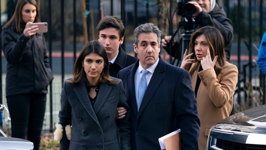 Michael Cohen arrive at federal court holding the arm of his wife. His adult children walk behind.