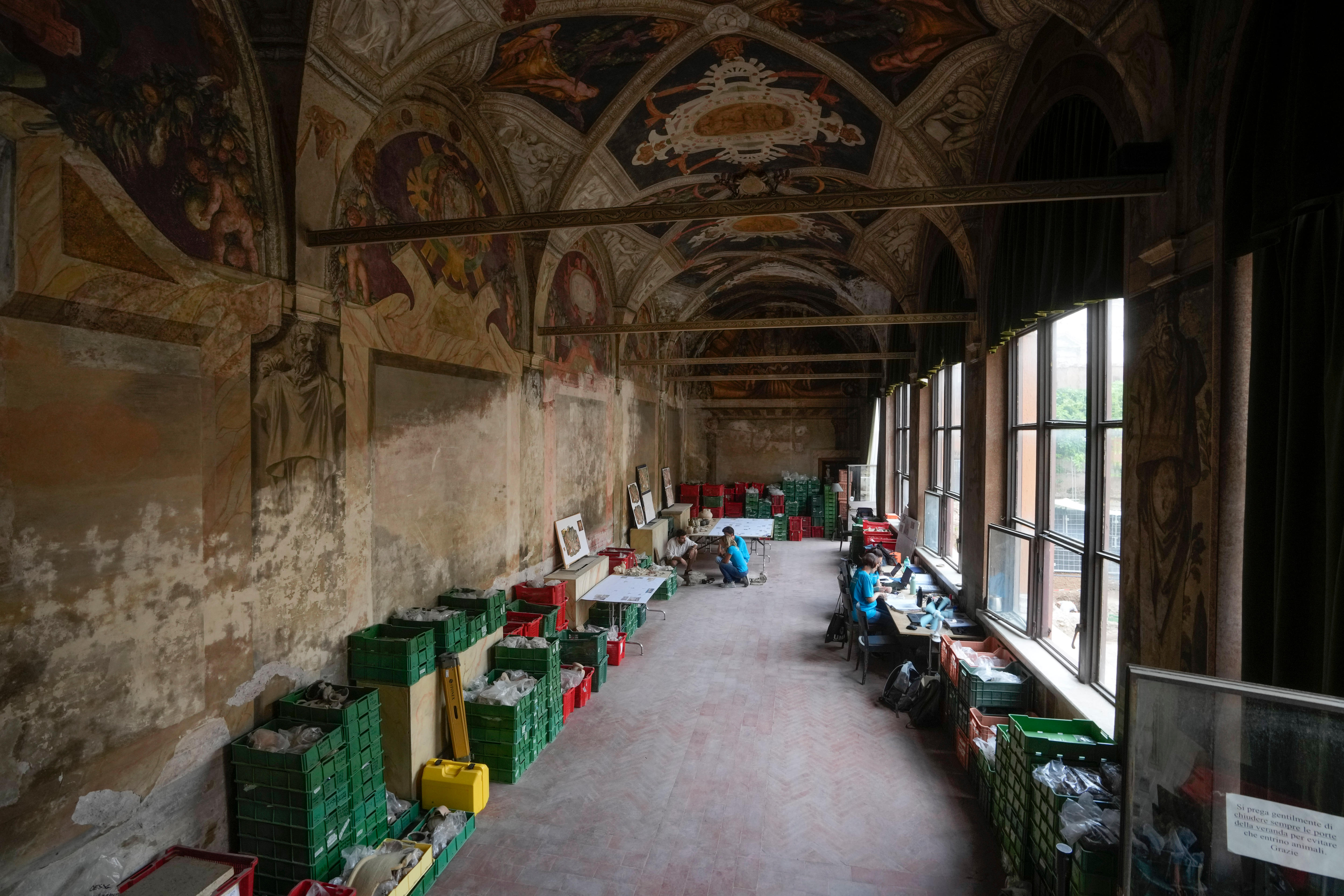 A large domed cathedral room with crates on either side of the wall full of discovered roman artifacts