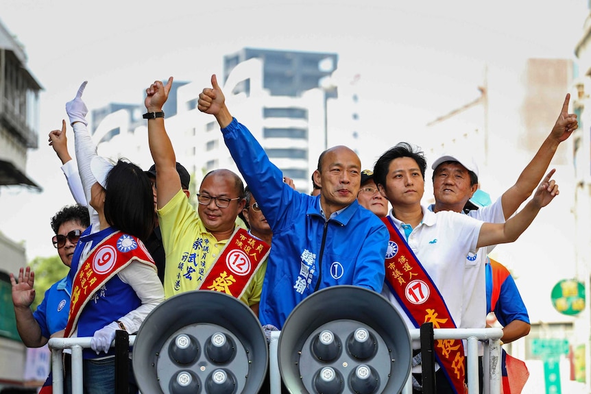 Kaohsiung mayor-elect Han Kuo-yu flanked by colourful supporters on cherry picker with large megaphones clipped to its front