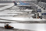Tractors remove snow from the ground at Manchester Airport